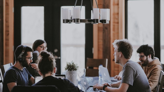 A group of people working on laptops together around a shared table.